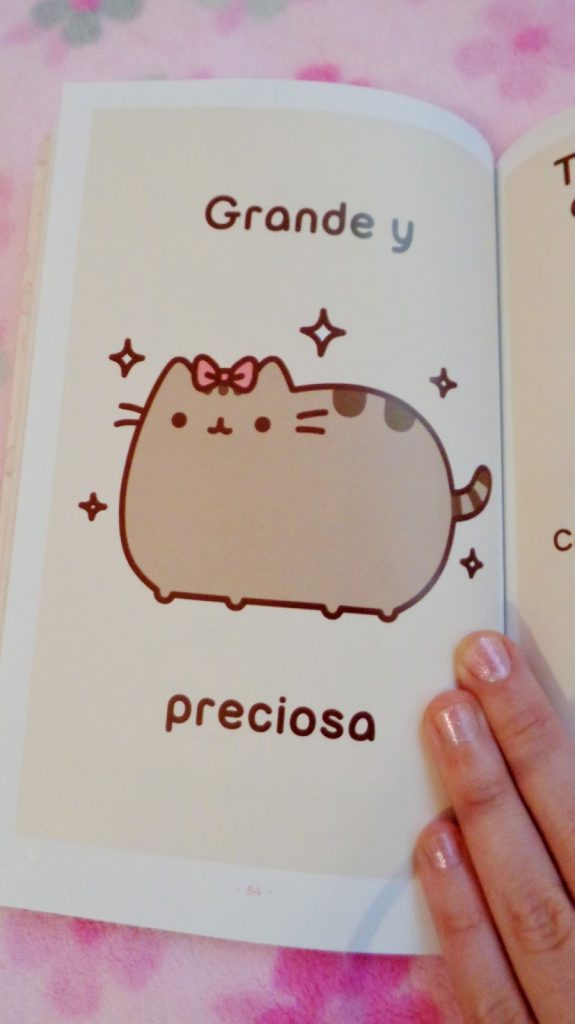 Fotografía de una página del libro de Pusheen, con la gatita gorda y grande, con un lazo rosa.