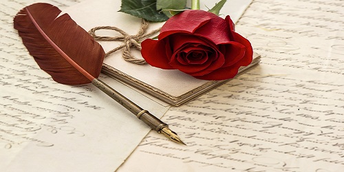 Rosa roja y un bolígrafo-pluma terminado en pluma de ave sobre una carta de amor.